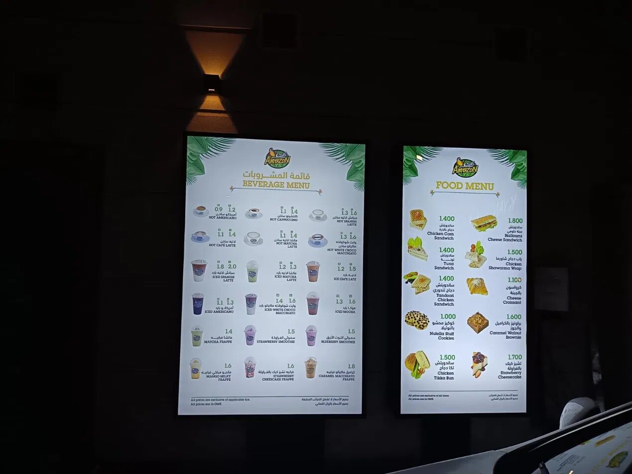 Backlit Café Amazon menu boards mounted above the service counter